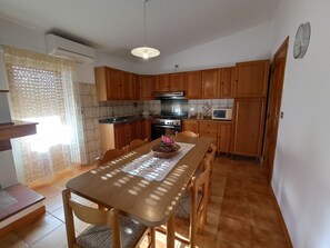 A kitchen with wooden cabinets, a dining table with chairs, a microwave, and a stove.