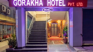 La entrada al Hotel Gorakha Pvt. Ltd., con una escalera que conduce al vestíbulo, un letrero de bienvenida y plantas en macetas.