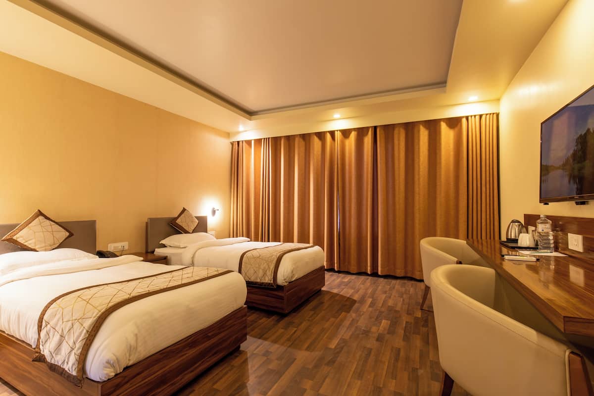 Habitación de hotel con dos camas, un escritorio y una silla.