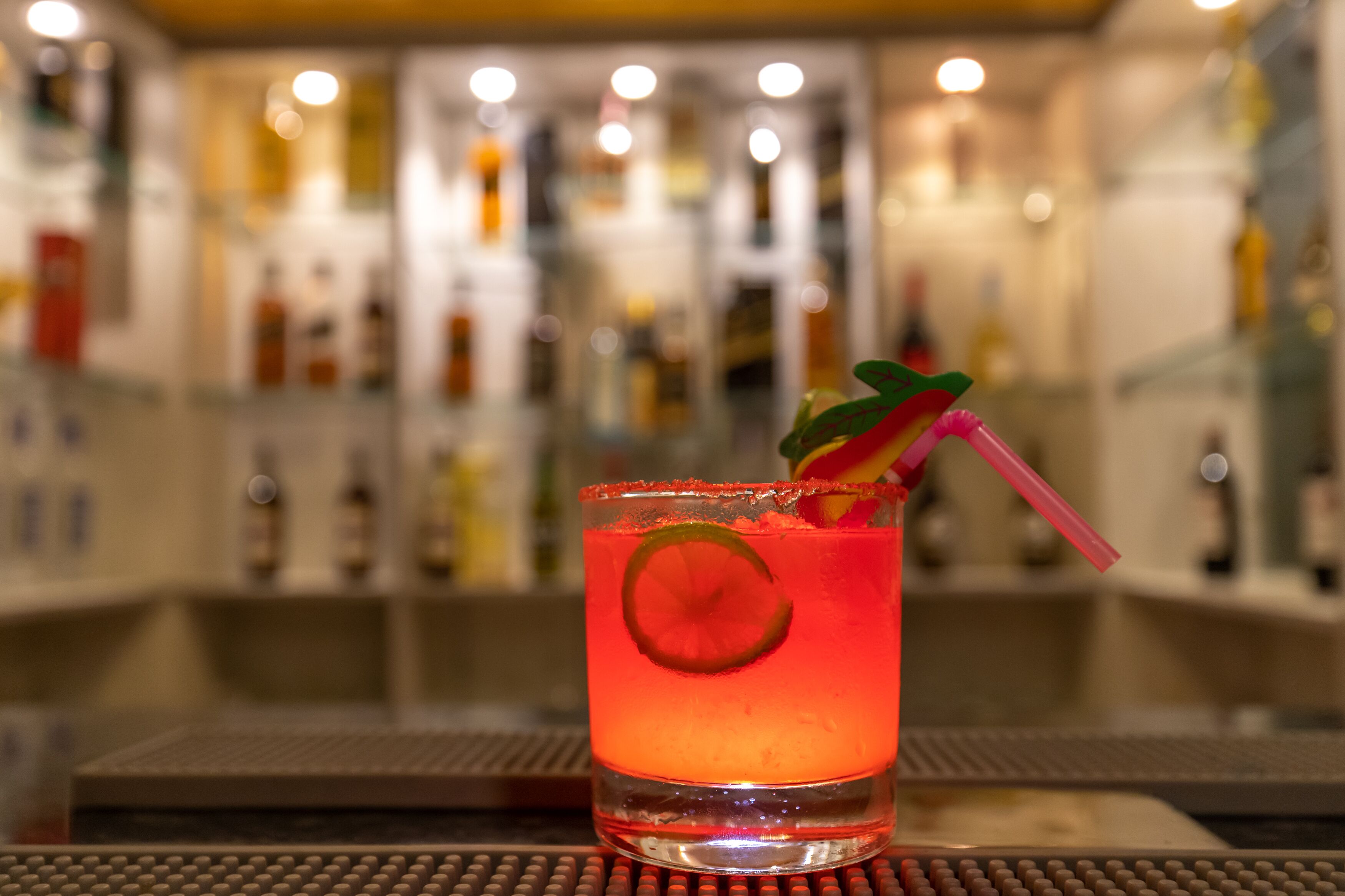 Cocktail-lasi, jossa on limenviipale koristeena, baaritiskillä.