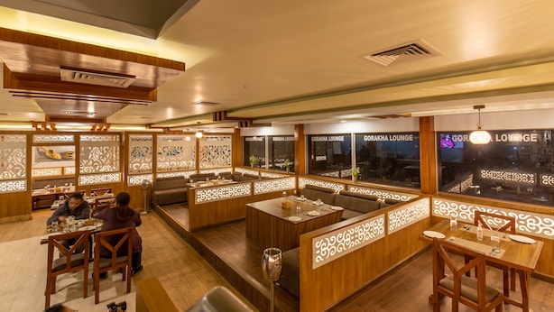 Un restaurante con decoración de madera, varias zonas de estar y grandes ventanales con vistas a la ciudad.