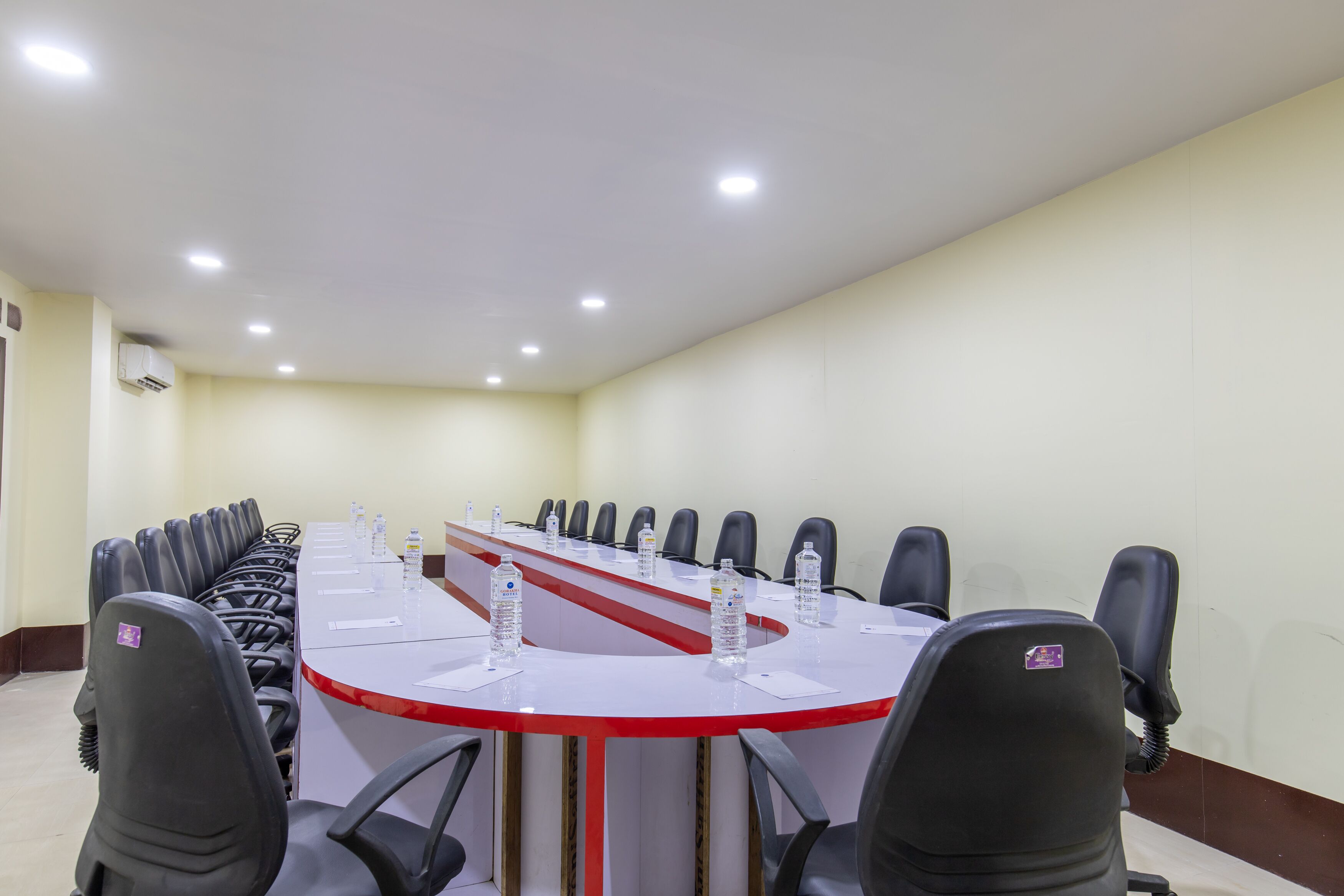 A conference room with a long table, black chairs, and water bottles.