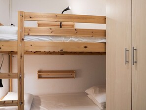 A bunk bed room with a wooden bunk bed, a small shelf, and a wardrobe. - Modern Apt in Val Thorens - 4 Pers, Balcony, Ski-In/Ski-Out, Near Shops & Restaurants (Val Thorens)