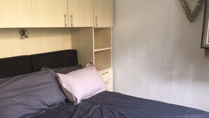 A bed with dark bedding, a headboard, and a wooden wardrobe with handles. - Modern Apt in Val Thorens - 4 Pers, Balcony, Ski-In/Ski-Out, Near Shops & Restaurants (Val Thorens)