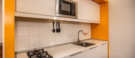 A kitchen with white cabinets, a stainless steel microwave, a gas stove, and a sink.
