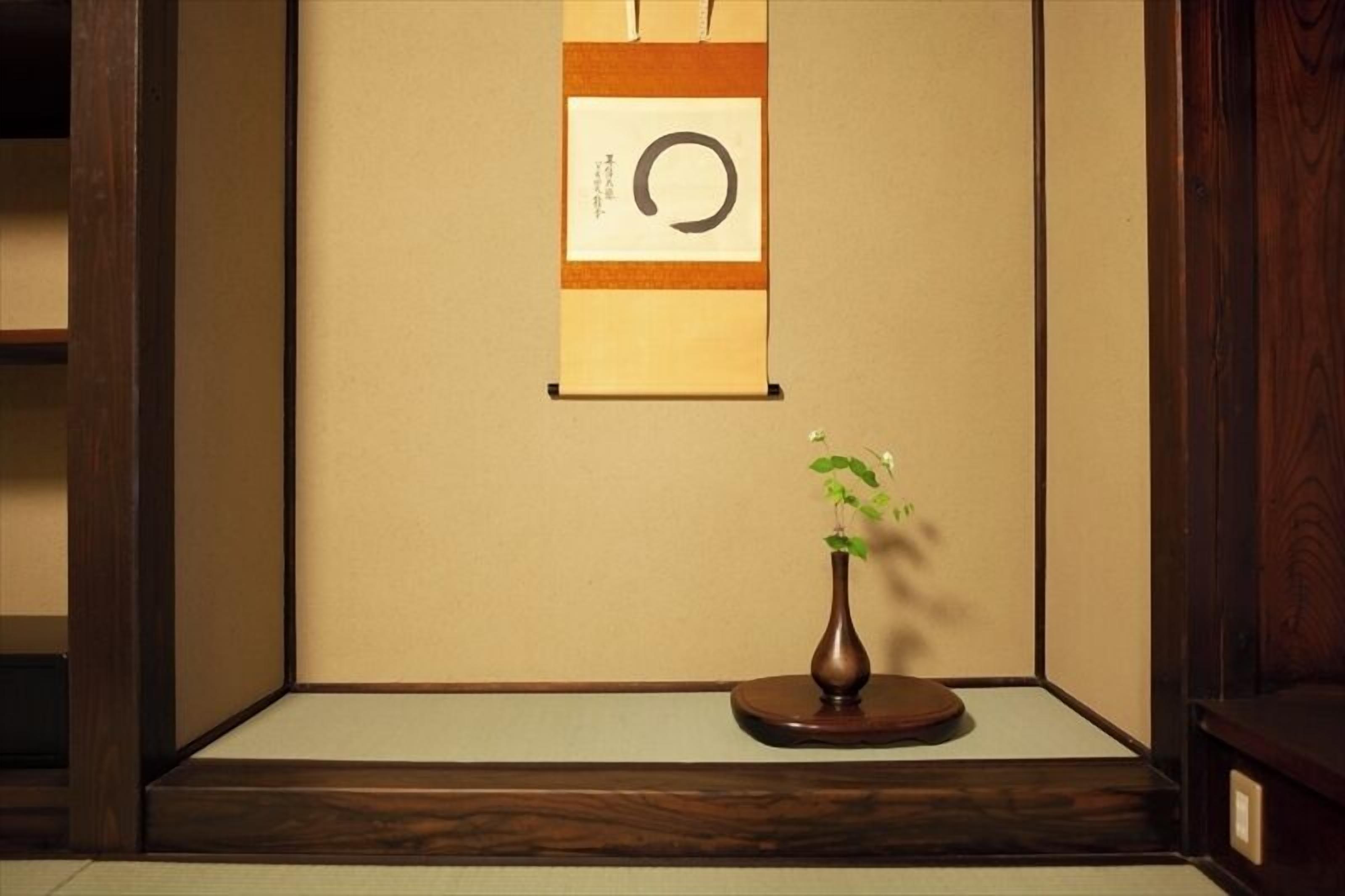 Um quarto japonês tradicional com tatames, um painel shoji e uma pequena mesa de madeira com um vaso de flores.
