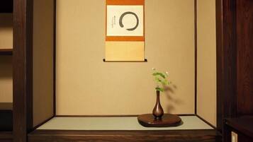 Um quarto japonês tradicional com tatames, um painel shoji e uma pequena mesa de madeira com um vaso de flores.