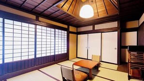 A traditional Japanese room with tatami flooring, sliding doors, and a low ceiling with a wooden beam structure. - Kumeya (Komoro)