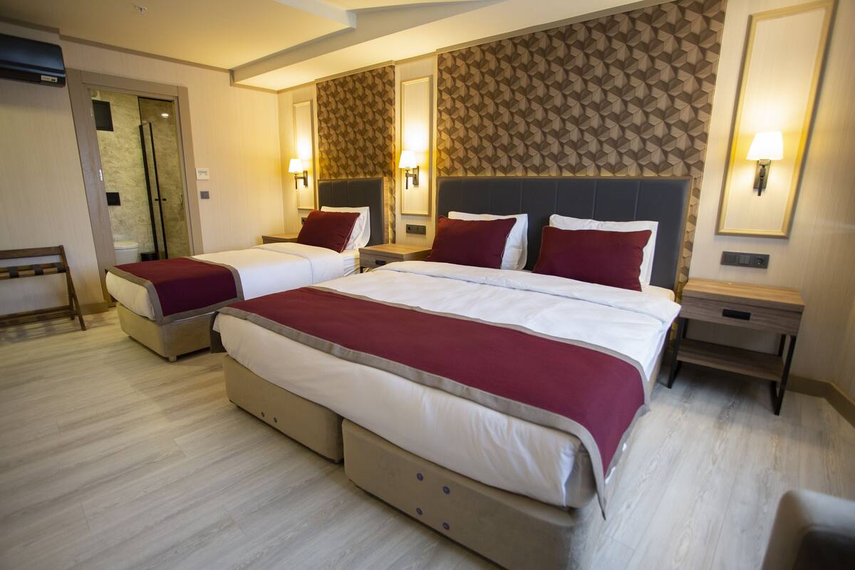 A hotel room with two beds, a bathroom, and a shower.