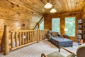 Relax in a spacious room with a high ceiling and wooden beams, featuring a cozy seating area with a sofa and cushioned bench.