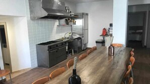 A modern kitchen with a long dining table, chairs, and a bottle of wine. - Vico rural cave house, ideal for large groups (Freila)