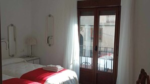 A hotel room with a bed, a nightstand, a mirror, a window with curtains, and a patterned floor. - Vico rural cave house, ideal for large groups (Freila)