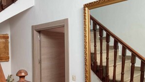 A staircase with wooden balusters, a closed door, and a large mirror with an ornate gold frame. - Vico rural cave house, ideal for large groups (Freila)