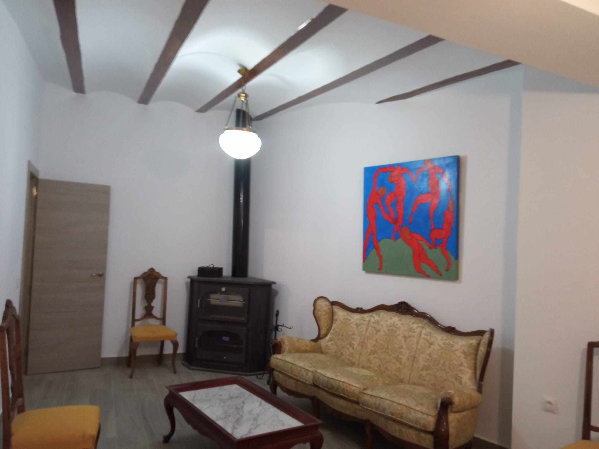 Un salon avec un canapé, des fauteuils, une cheminée et un tableau accroché au mur.