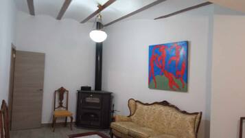 Un salon avec un canapé, des fauteuils, une cheminée et un tableau accroché au mur.