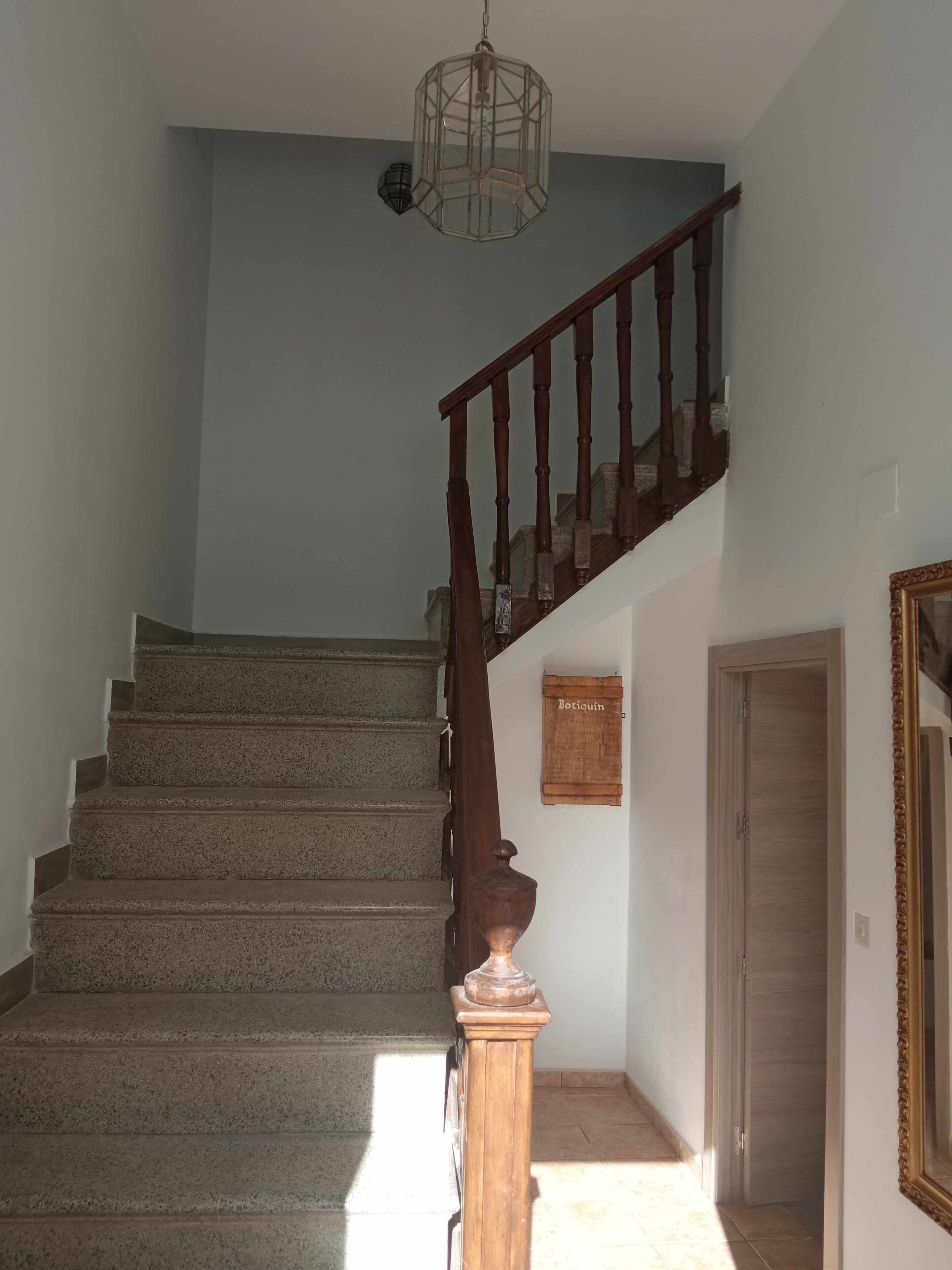 A staircase with a wooden handrail and a geometric light fixture above.