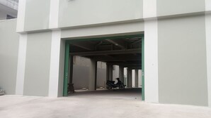 Ein Gebäudeeingang mit türgrünem Rahmen, einem Betonboden und einem abgestellten Roller.