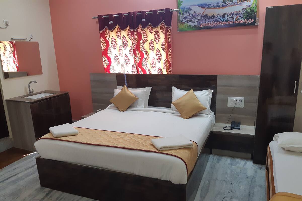 Une chambre d’hôtel avec un grand lit, une table de chevet, une commode, un miroir, une armoire et une salle de bain avec un lavabo.