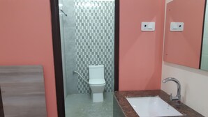 A bathroom with a glass shower enclosure, a white toilet, and a granite countertop sink.