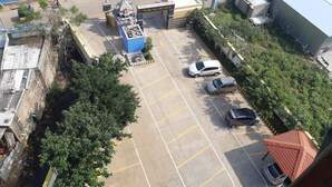 An aerial view of a parking lot with several cars, a small shrine, and a building with a blue roof.
