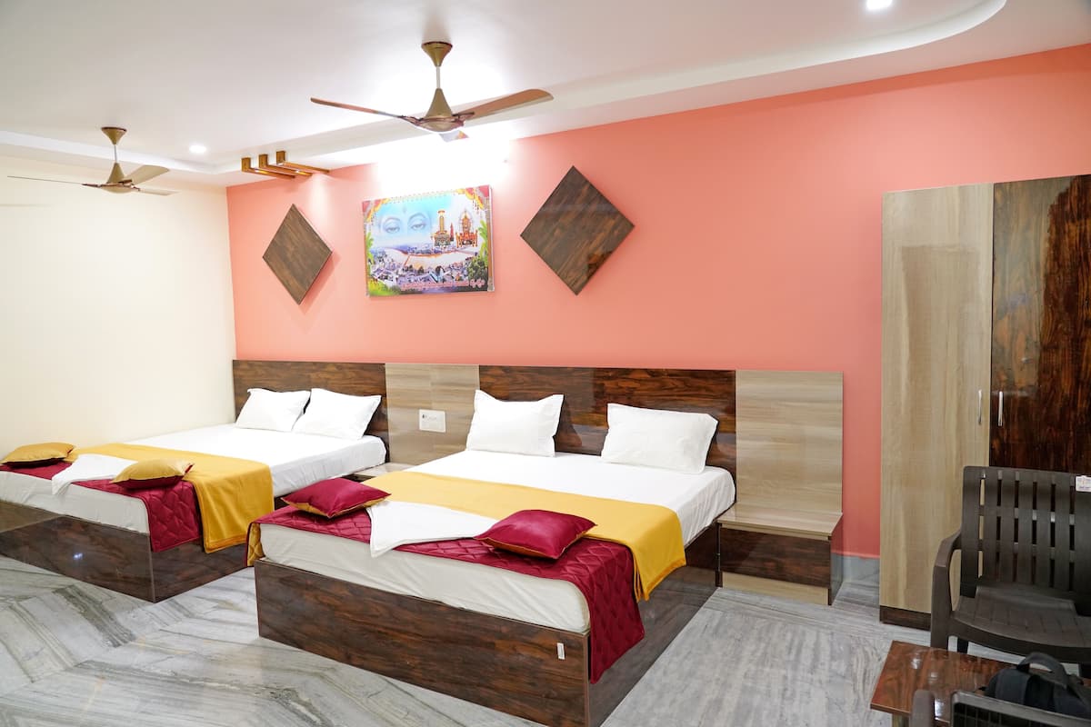 Une chambre d’hôtel avec deux lits, une tête de lit en bois, un ventilateur de plafond et un tableau au mur.
