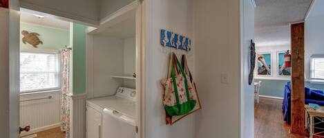 A laundry room with a washing machine, a drying rack, and a wall-mounted drying rack.