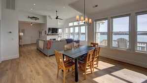 A spacious living area with a dining table, chairs, and a view of the water.