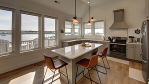 A modern kitchen with large windows, a central island, and a view of the water.