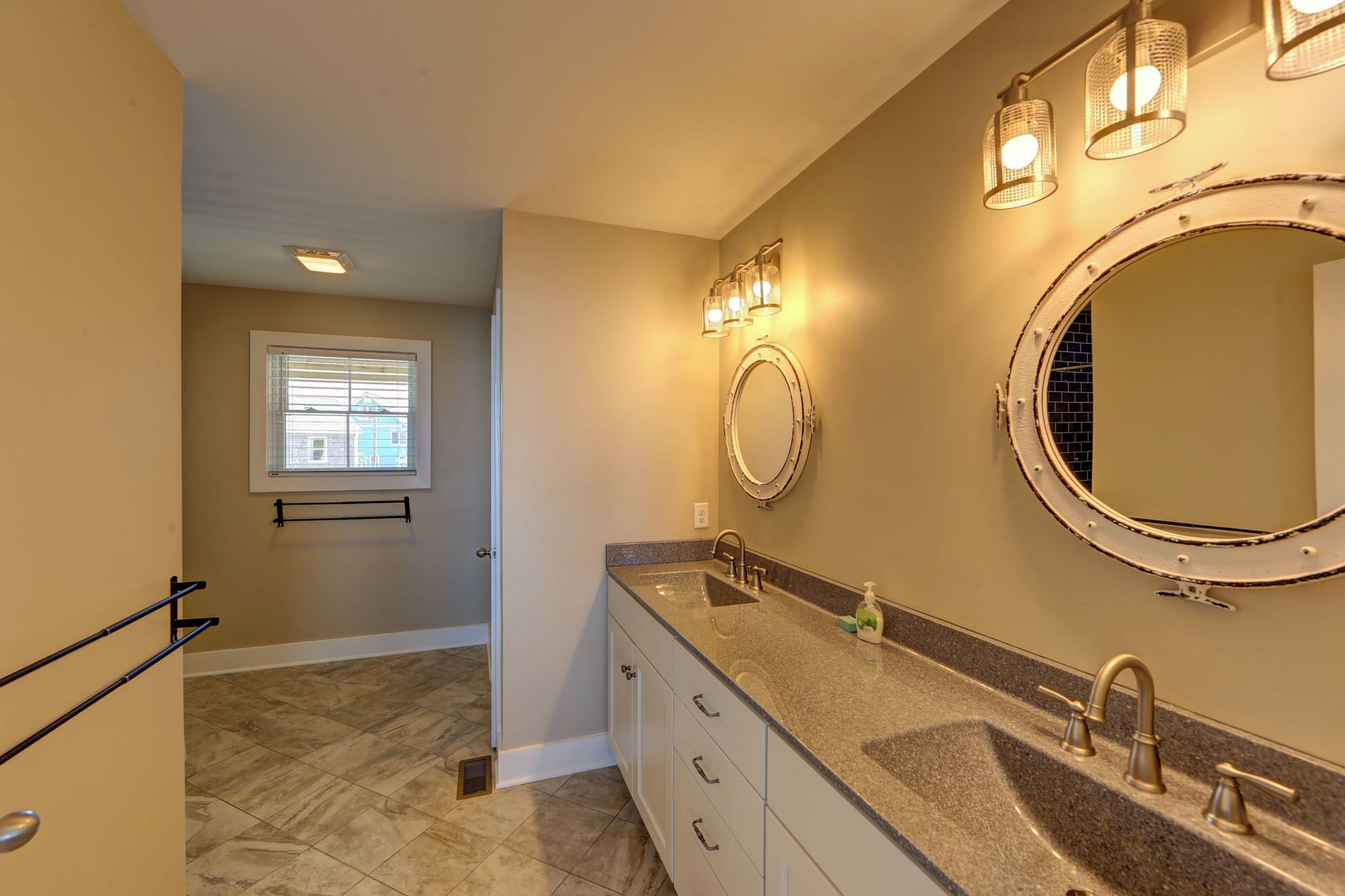 Your elegant master bathroom features dual vanities with granite countertops, nautical mirrors, and warm lighting for a luxurious start to each morning.