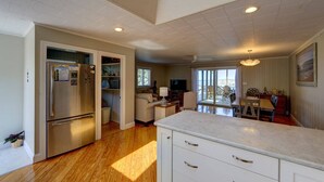 Una cocina amplia con refrigerador empotrado, una zona de comedor con mesa y sillas, y un balcón con vistas.