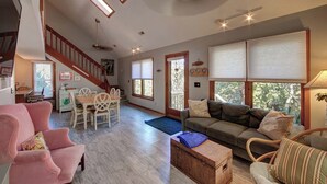 A spacious living room with a staircase, a dining area, and a cozy seating area with a sofa and chairs. - Charlotte's Place - Ocracoke Island (Ocracoke)