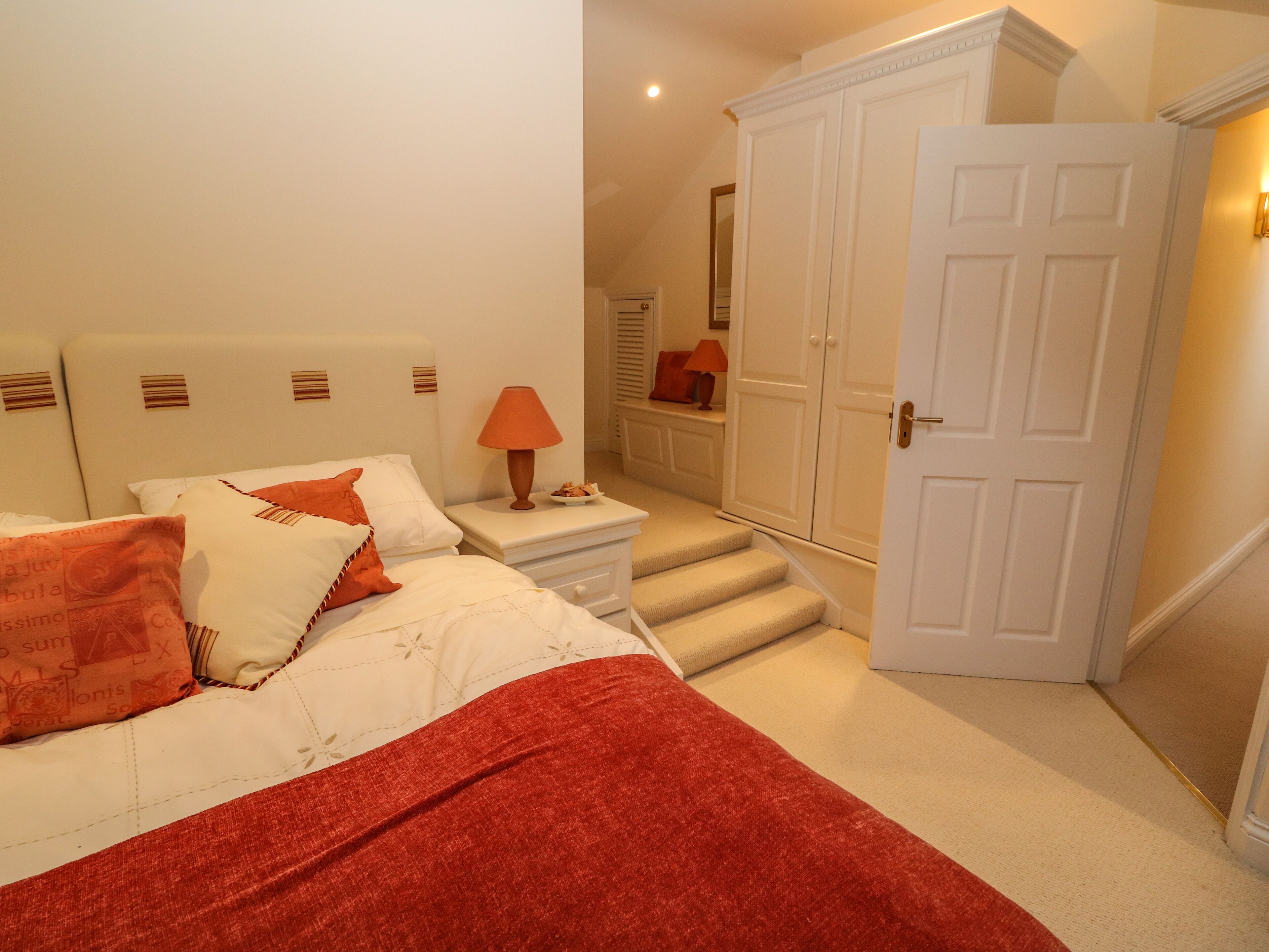 A bedroom with a bed, nightstand, lamp, and wardrobe.