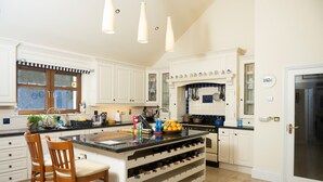 Una cocina amplia con armarios blancos, una isla grande con espacio para guardar vino y un horno empotrado.