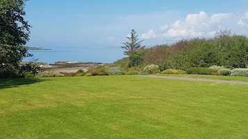 A grassy field with a pathway leading to a coastal area.