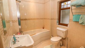 A bathroom with a bathtub, toilet, sink, and a window.