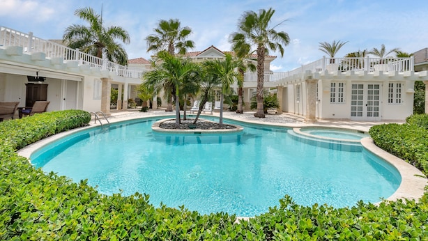 A pool surrounded by palm trees and a white building with a balcony. - Luxury 2-level villa in Punta Cana (Punta Cana)