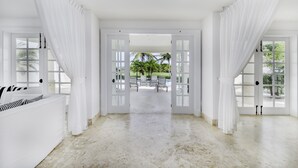 A spacious room with white walls and a marble floor, leading to a balcony with a view of palm trees and a lawn. - Luxury 2-level villa in Punta Cana (Punta Cana)