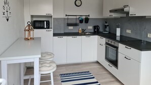 Une cuisine moderne avec des meubles blancs, un four à micro-ondes, une machine à café et une horloge murale.