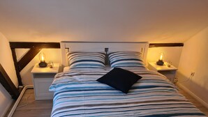 Une chambre à coucher avec une couvre-lit à rayures, deux lampes de chevet et un oreiller noir.