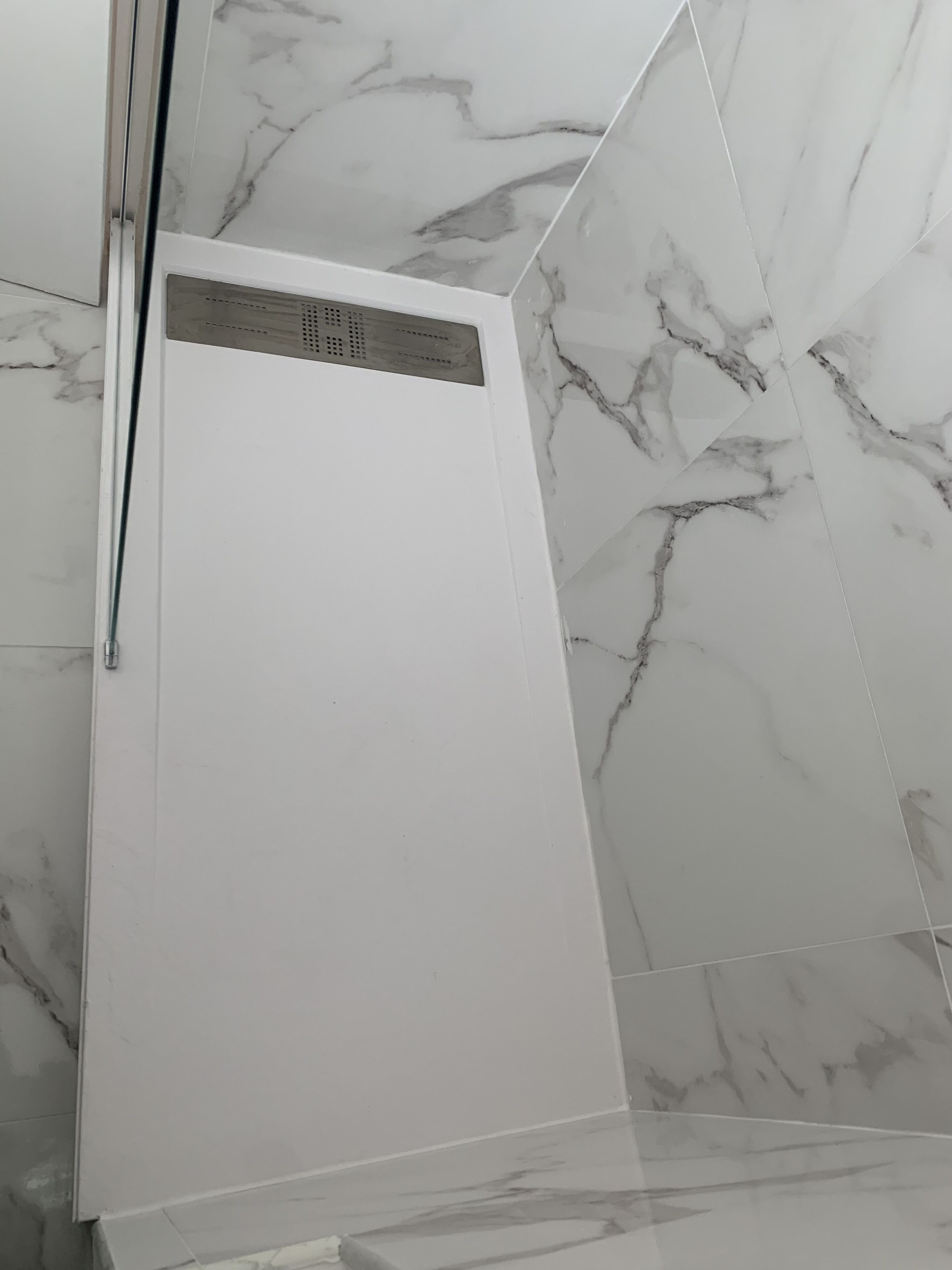 Un baño con cabina de ducha blanca y paredes de mármol.