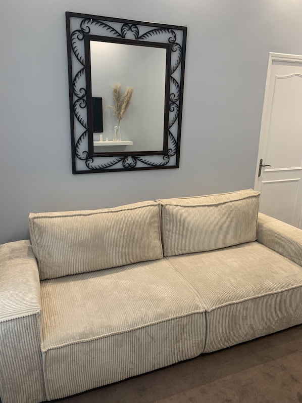 Un sofá de corcho color beige con un espejo decorativo encima.