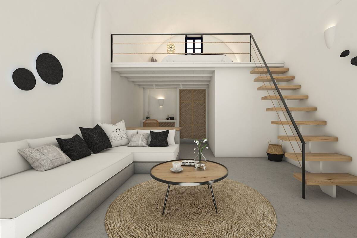 A modern living room with a white sofa, a round coffee table, a staircase with wooden steps, and a view into the kitchen.