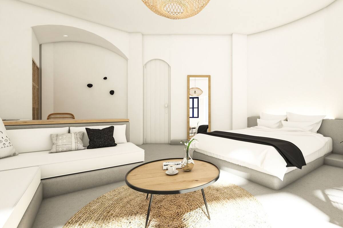 A modern, minimalist bedroom with a bed, a sofa, a round coffee table, and a chair.