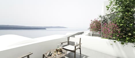 Una terrazza con tavolo e sedie, vista su uno specchio d'acqua e una terraferma in lontananza.