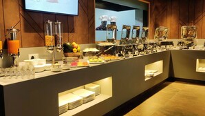 Montaje de bufé con diversos alimentos y dispensadores de bebidas.