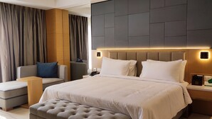 Una habitación de hotel moderna con una cama grande, un sofá, una mesita y una zona de estar con un banco.