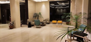 Um lobby moderno com piso de mármore, áreas de estar e plantas em vasos.