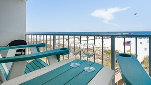 Un balcon donnant sur la plage, deux verres à vin vides et un drapeau.
