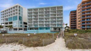 Un hôtel en bord de mer, avec plusieurs étages, un parking souterrain et un passage piétonnier donnant accès à la plage.