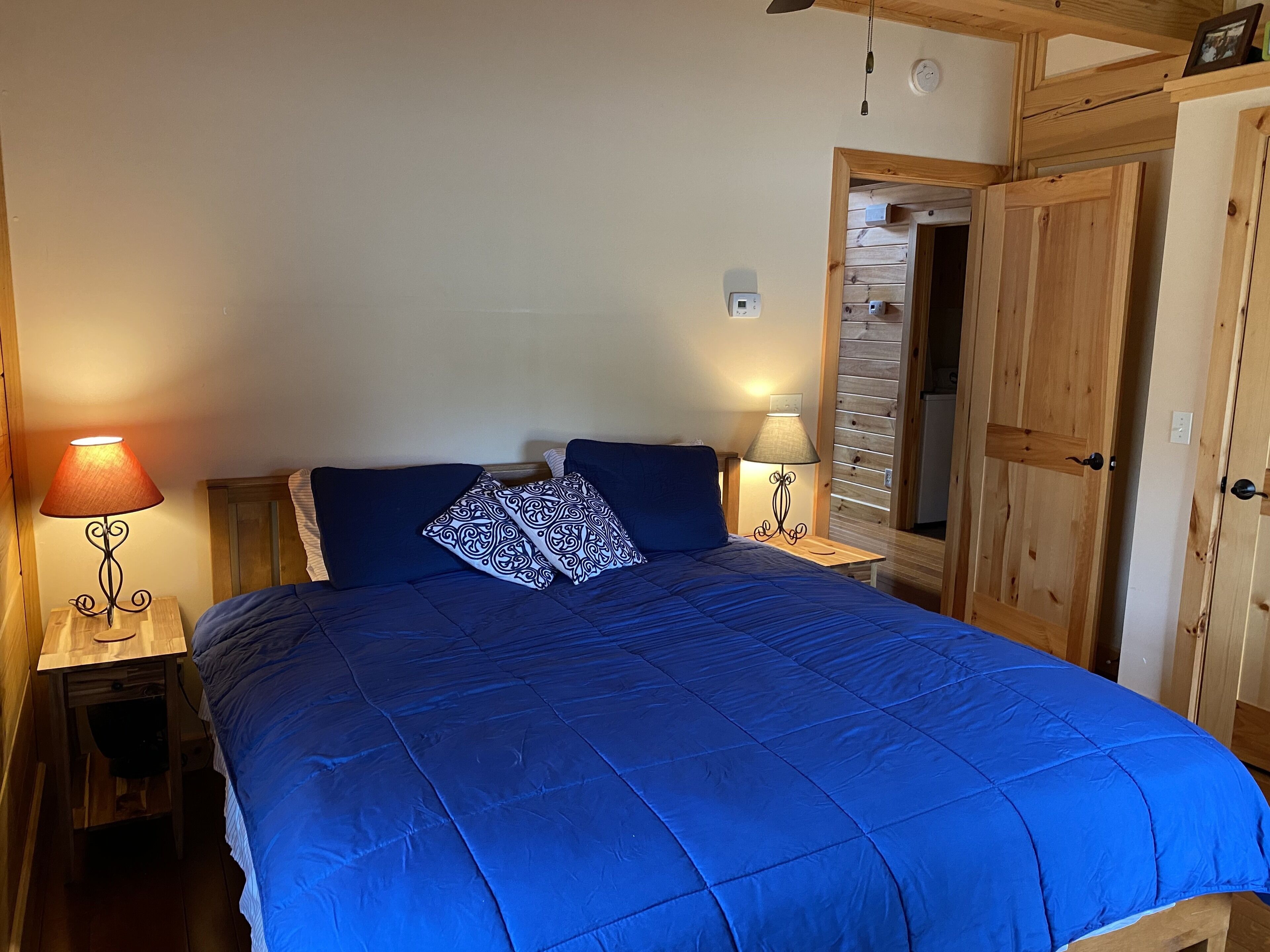 A bedroom with a large bed, two bedside lamps, and wooden doors.